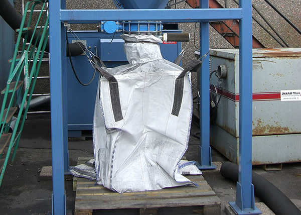 BEASS filter separator discharging fine dust or material into a secured industrial big bag, demonstrating clean, manual emptying in a fixed vacuum system setup.
