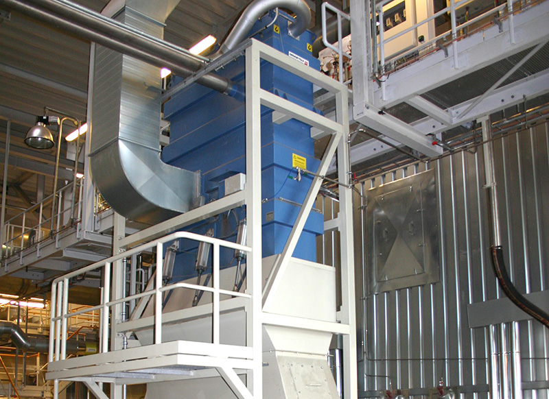Installed BEAT filter separator system inside an industrial building, connected to ducting and surrounded by access platforms, showing its integration in a central vacuum and filtration setup.