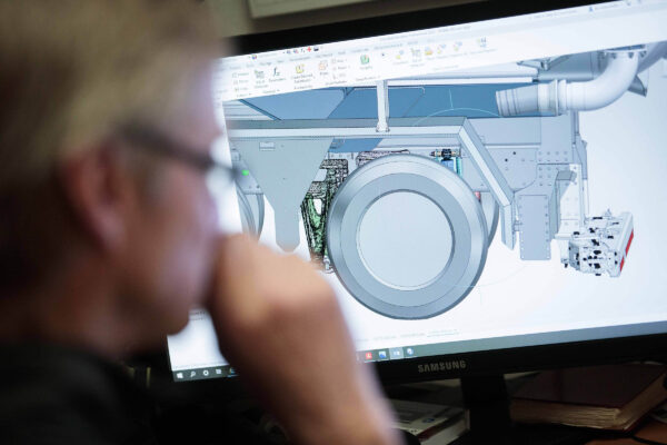 Engineer analyzing a 3D CAD model of a vacuum suction unit on a computer screen