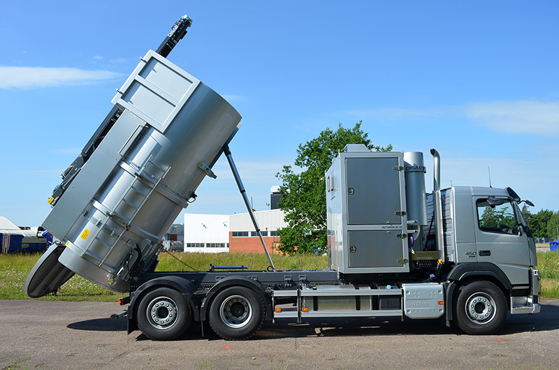 DISAB Vacturion™ DL10 vacuum loader with its cylindrical tank raised for discharge, parked on a paved surface, highlighting its powerful suction capacity and hydraulic tipping mechanism.